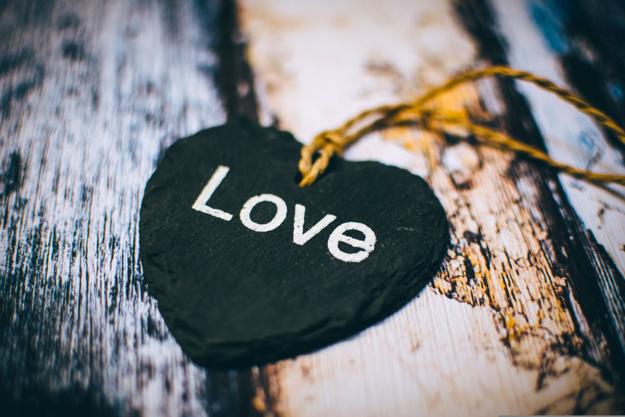 A slate heart with Love written on it tied with a golden string
